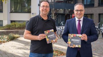Bild: Bürgermeister Thomas Kerkhoff (rechts) und der Integrationsbeauftragte Bruno Wansing stellen das neue Kochbuch "Bocholt is(s)t bunt" vor (Copyright: Stadt Bocholt)