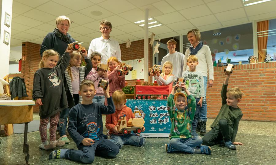 Foto der Spendenübergabe bei der Kindertageseinrichtung St. Paul. V. l. n. r. Erzie- herin Birgit Hullerum; Jürgen Elmer, Geschäftsführer der Stadtwerke Bocholt GmbH (SWB); Elija Cürsgen, Auszubildender bei der Bocholter Energie- und Wasserversorgung GmbH (BEW) sowie Maria Kolks, Leiterin der KiTa St. Paul mit einigen Kindergartenkindern. 