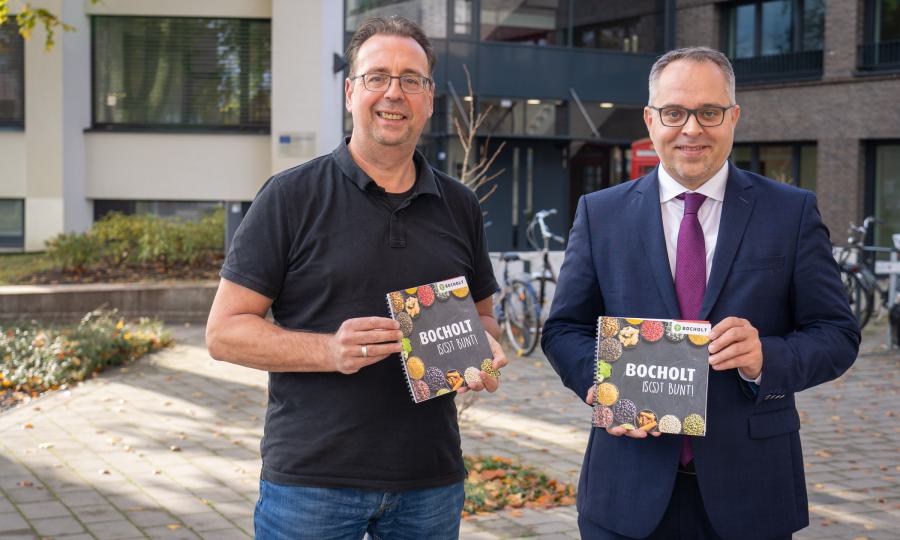 Bild: Bürgermeister Thomas Kerkhoff (rechts) und der Integrationsbeauftragte Bruno Wansing stellen das neue Kochbuch "Bocholt is(s)t bunt" vor (Copyright: Stadt Bocholt)